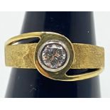An 18ct yellow gold solitaire diamond ring, set in a rub-over setting with a polished and textured