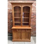 A modern stripped pitch-pine kitchen dresser/bookcase, with a pair of glazed doors enclosing