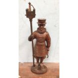 A cast iron coppered fire-companion set, the stand modelled as a Yeoman, 80cm high