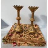 A pair of brass altar candlesticks with scalloped pierced rims and clover pierced bases raised on