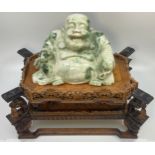 A carved jadeite figure of the seated happy buddha, 14cm high, raised on a finely carved boxwood and