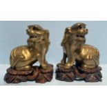 A pair of heavy copper alloy Chinese lions in a seated position looking over their shoulders, raised