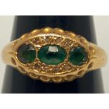 A gents 18ct yellow gold ring set with central oval emerald 'coloured' stone and flanked by two