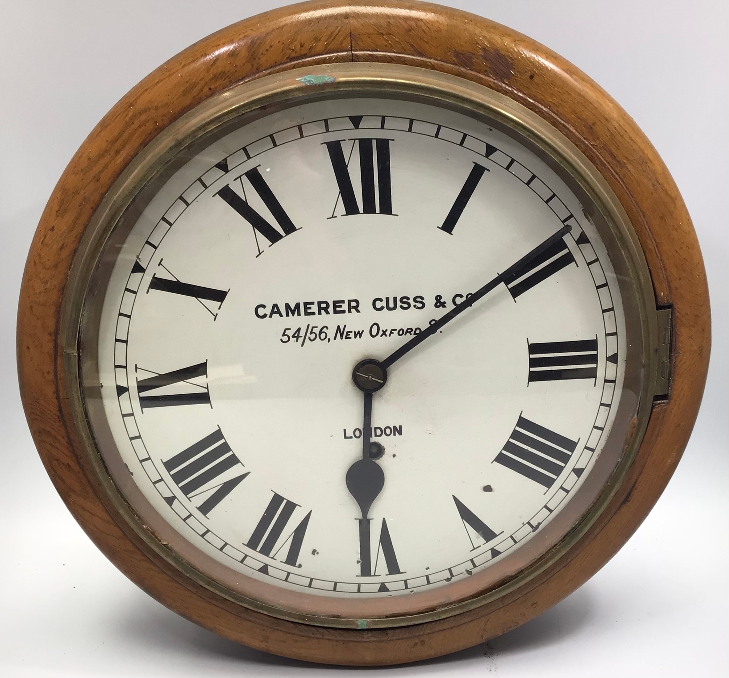 A mahogany cased circular wall clock with white enamel dial and black roman numerals, marked to