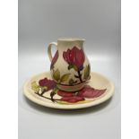 A Moorcroft pottery plate and jug decorated in the Magnolia pattern, designed by Walter Moorcroft,