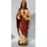 A plaster statue of Jesus Christ, his right hand raised in blessing, wearing a robe with Sacred