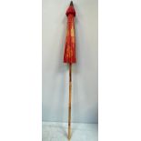 A Thai handmade garden parasol, painted with orange and gold flowers to red ground