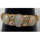 A ladies 18ct yellow gold ring set with three opals (central one chipped) interspersed with two rows