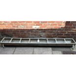 A large galvanised sectioned feeding / water trough, 245cm long