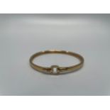 A 9ct gold bangle, with a square buckle design top, set with two small round diamonds, weight 8.0