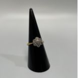 An 18ct yellow gold daisy style ring, set with 7 x round brilliant cut diamonds, total diamond