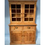 An Edwardian stripped pine dresser, the raised back with two glazed cupboards enclosing shelves,