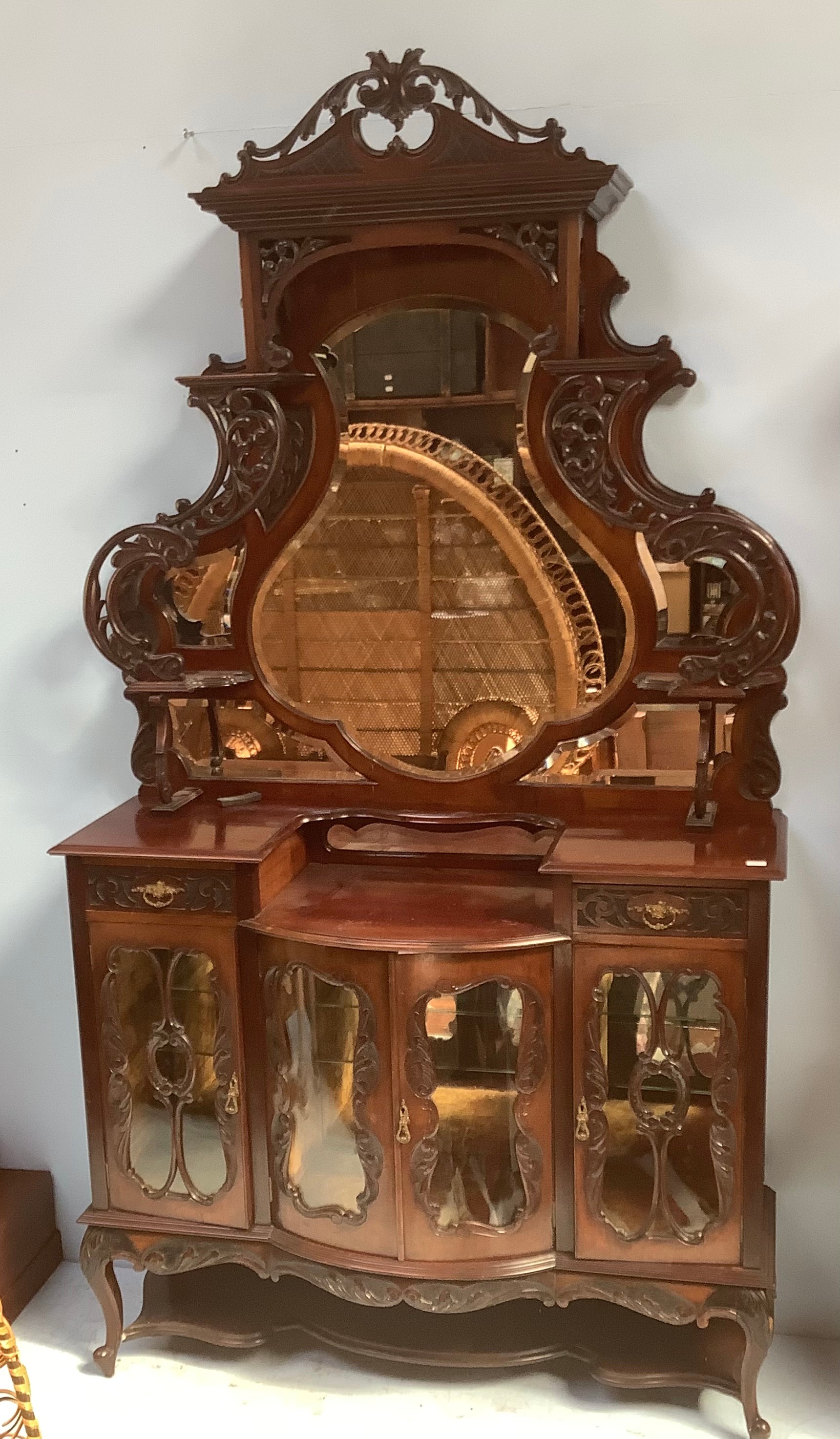 A Victorian stained walnut Roccoco revival tall mirror-back glazed sideboard, with central bow-front