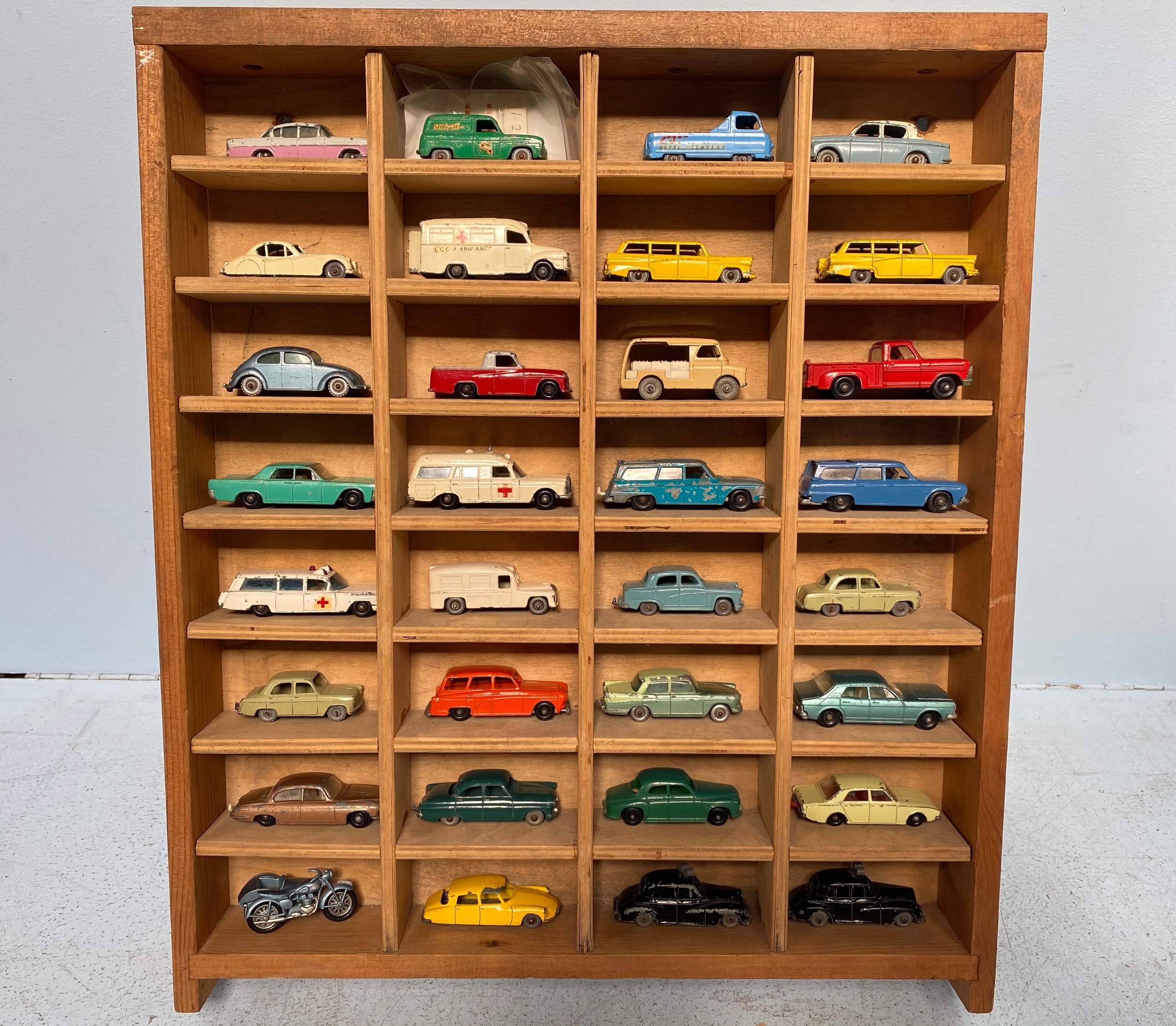 A collection of 32 loose play worn die-cast model vehicles, housed in wooden display case,