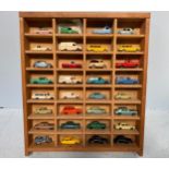 A collection of 32 loose play worn die-cast model vehicles, housed in wooden display case,