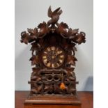 A German black forest carved cuckoo clock with twin fusee movement, ornately carved foliate case