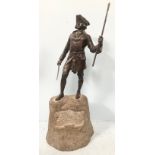 A bronze figure of an 18th century gent in tricorn hat and frock coat holding a sword in one hand