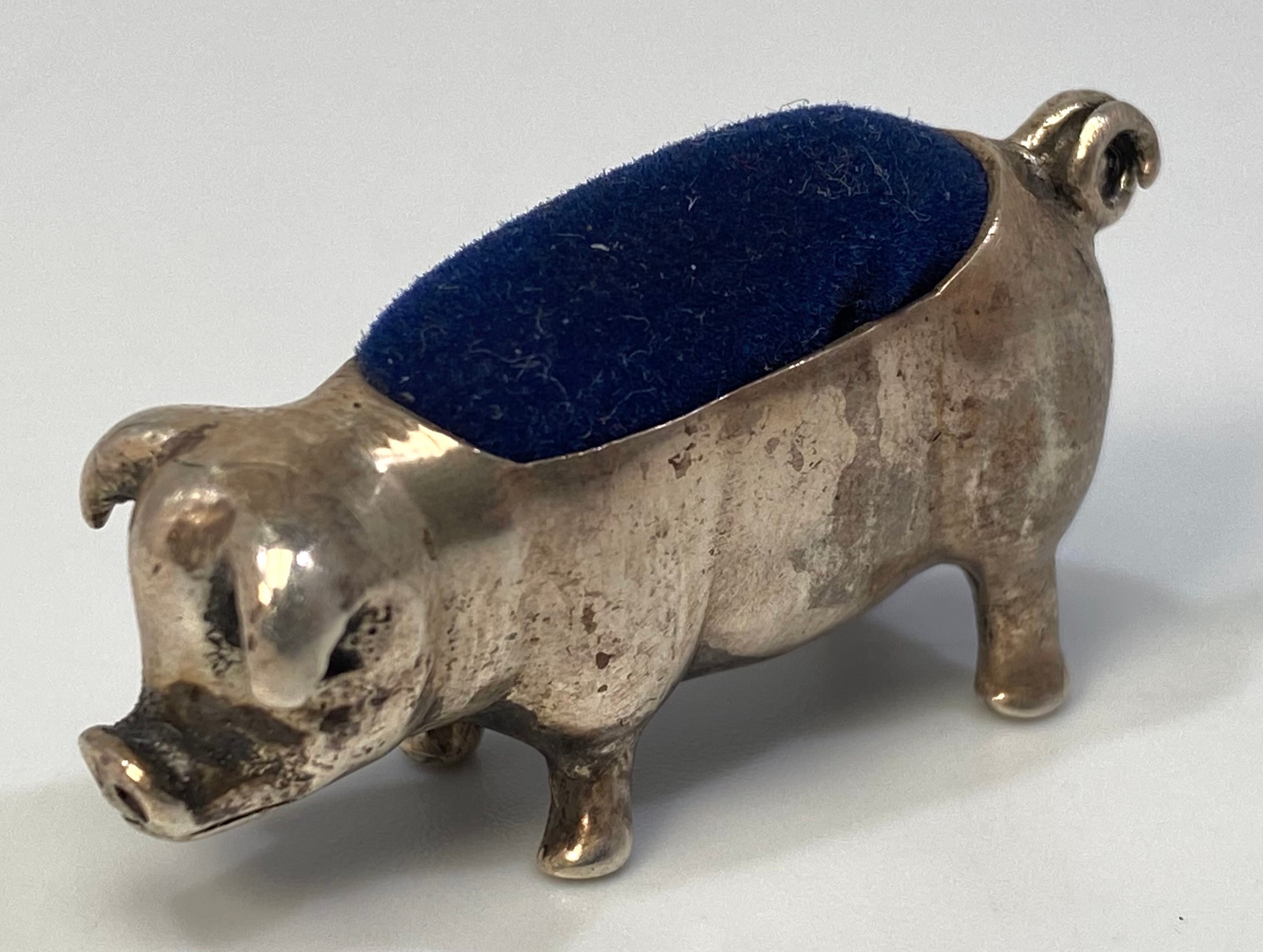 A silver pin cushion modelled as a pig with curled tail, stamped ‘925’, approximately 4cm long