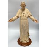 A large composite model of a Pope, possibly John Paul II, in long robes with crucifix necklace and