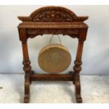 A carved oak framed floor-standing dinner gong, with foliate carved arched top, raised on scrolled