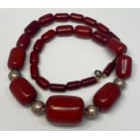 A cherry amber bakelite necklace with graduated barrel beads interspersed with silver plated round