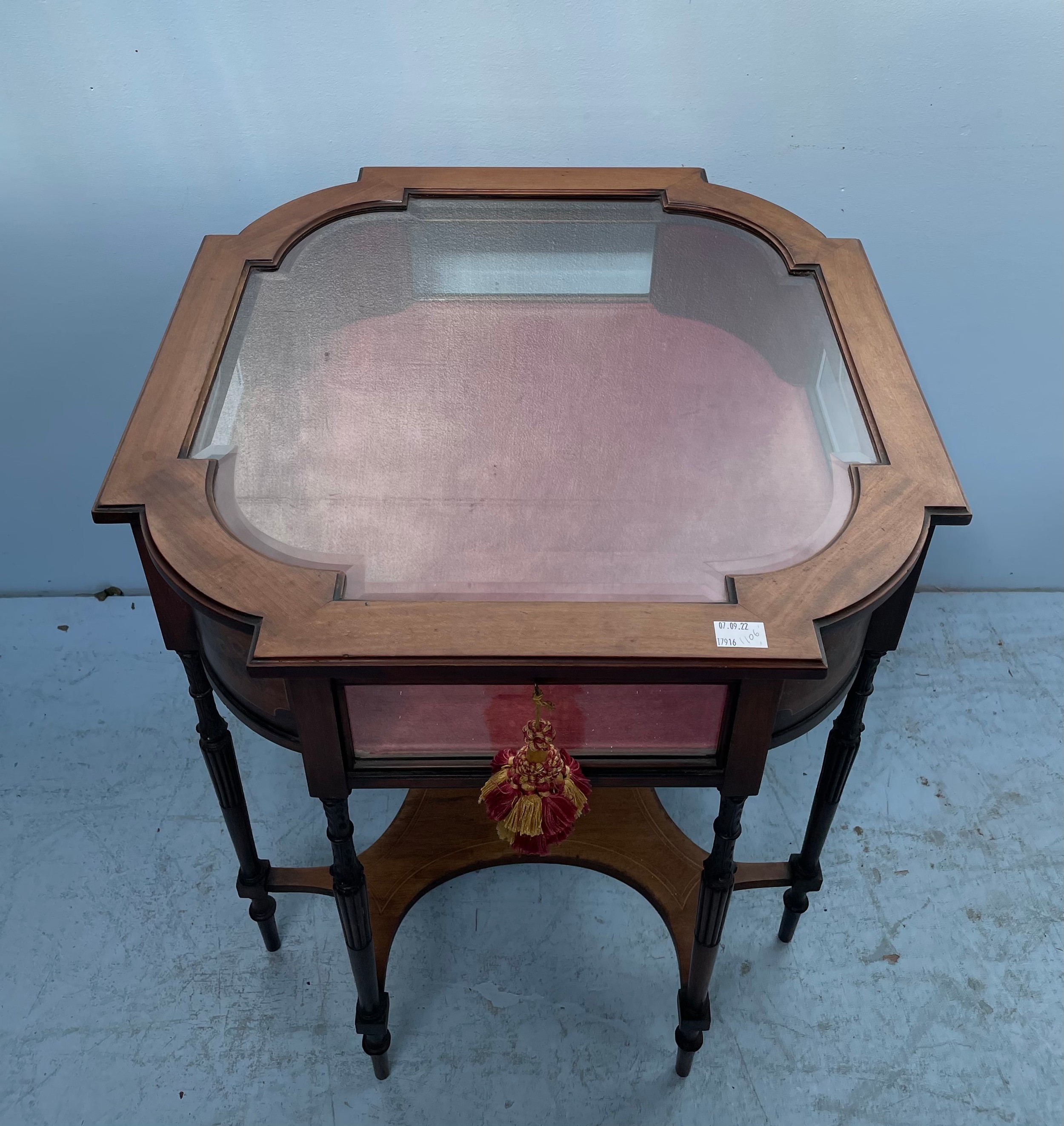 A stained walnut bijouterie table with shaped top, inlaid floral canted corners, red velvet lined