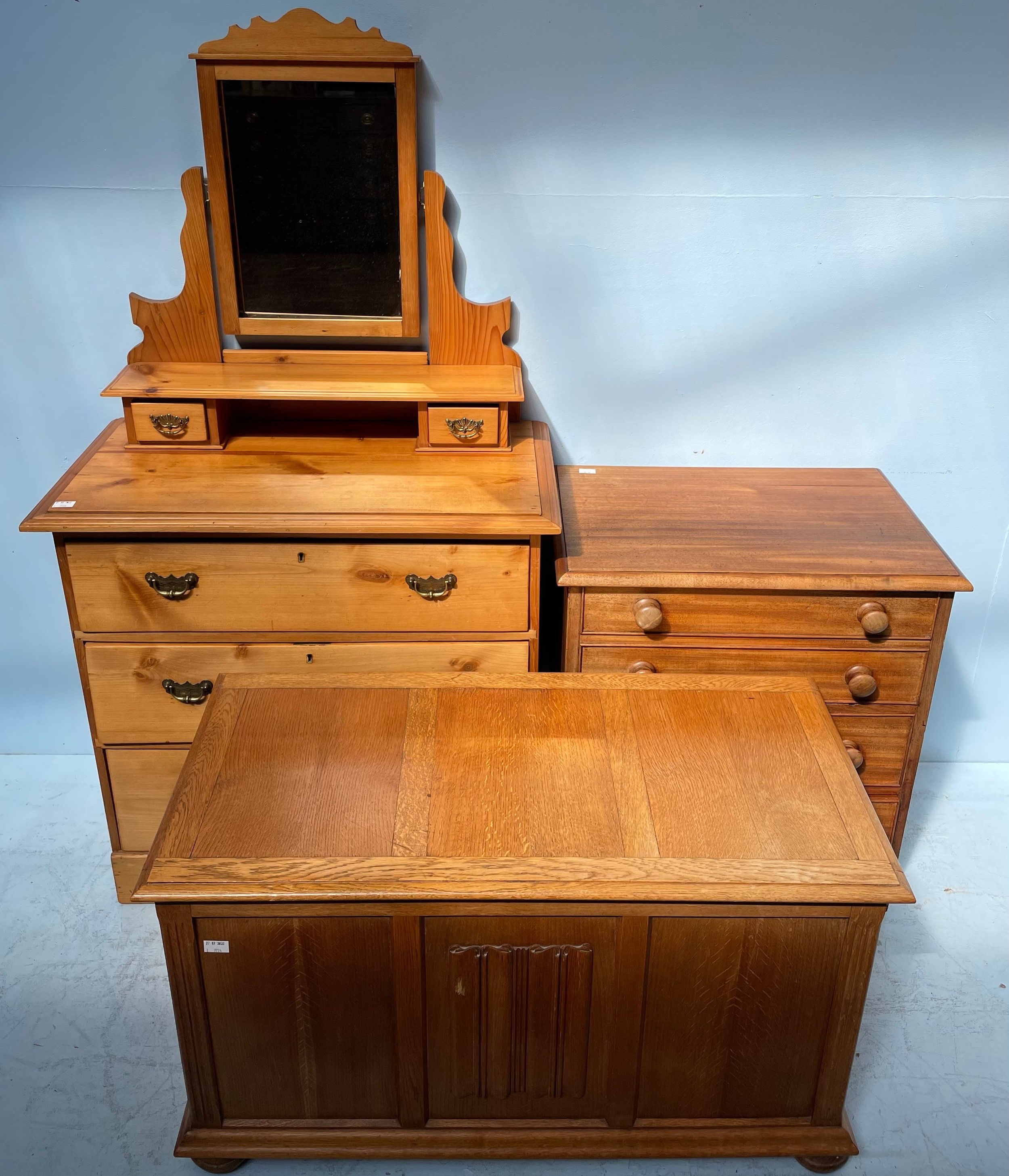 A pine dressing table with mirrored back above a chest of three graduated long drawers, raised on