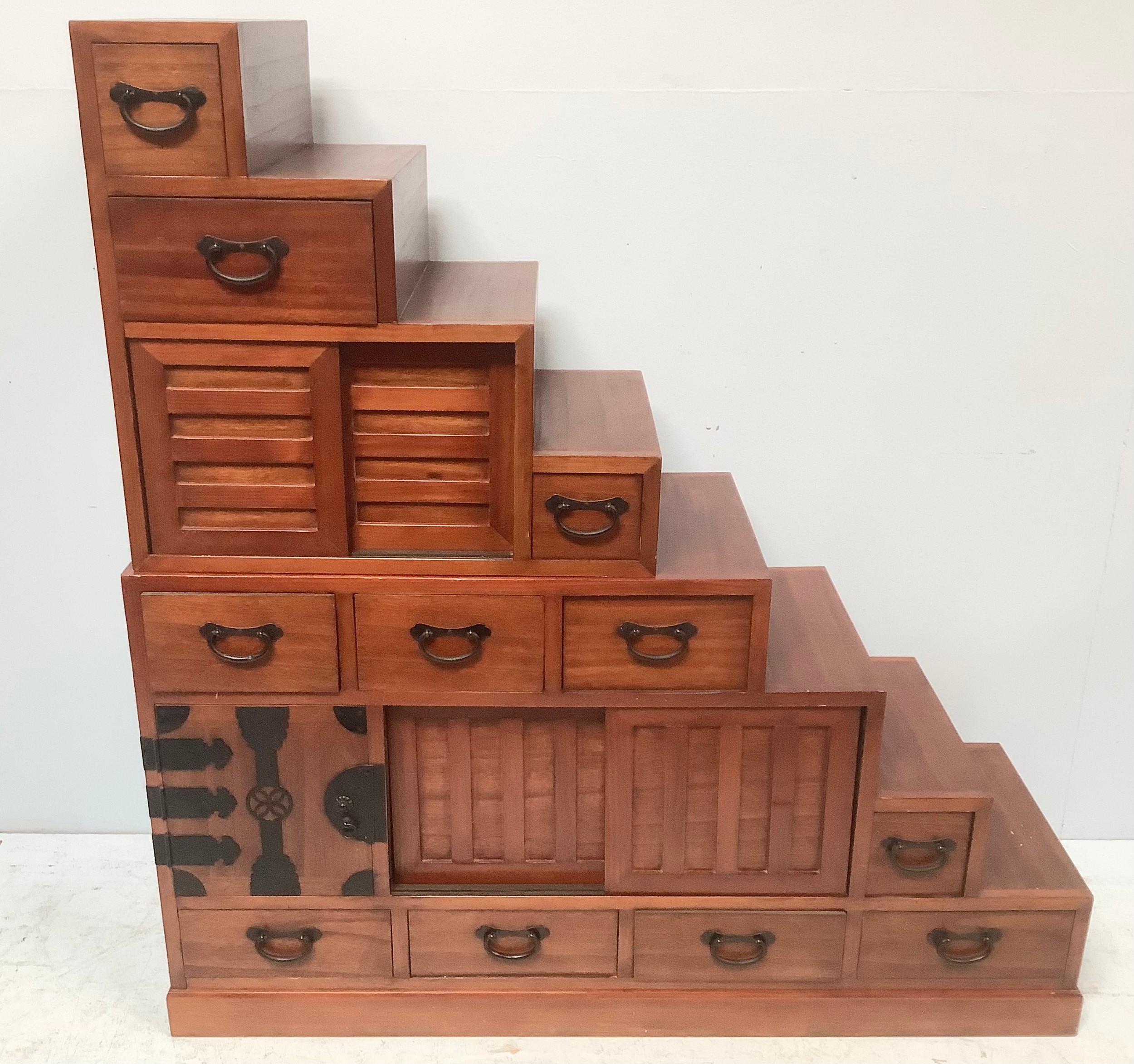 A 20th century Japanese Tansu stair storage system comprising various drawers with black metal