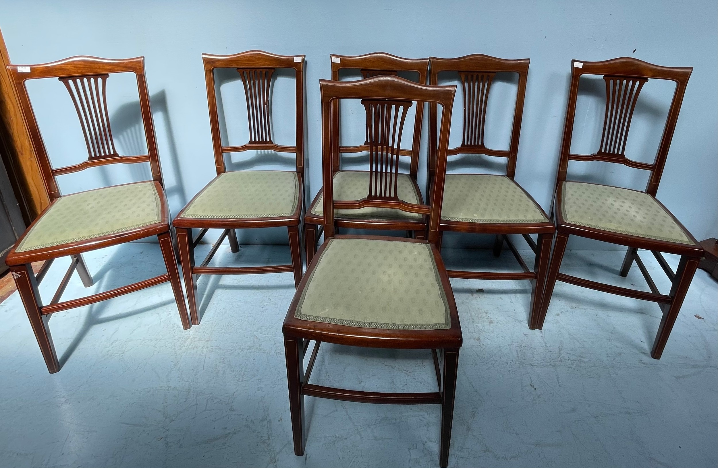 A set of six Edwardian mahogany standard chairs, with inlaid backs and pale green upholstered drop