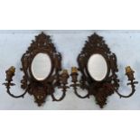 A pair of French bronze twin-branched wall sconces, central oval mirrored panels surrounded by