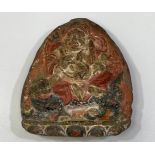 A 19th century Tibetan clay amulet painted with a Buddhist deity, possibly Vaishravana, riding a foo