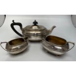 An Arts & Crafts silver three-piece bachelor’s tea service comprising teapot with ebonised finial