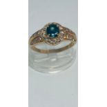 An 18ct yellow gold dress ring, set with an oval blue faceted stone to the centre with 14 x small