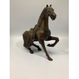 A Chinese bronze figure of a Tang horse, rising from a recumbent posture, 30cm high