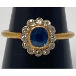 An 18ct gold ring, centrally set with an oval faceted sapphire stone, surrounded by 12x small