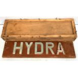 A name plate for HMS Hydra, formed of metal letters mounted to a wooden plaque, 88cm