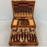 A silver-plated cutlery set housed in an Art Deco two tier oak canteen