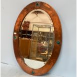 A Liberty & Co Arts & Crafts oval mirror with hammered copper frame, inset with heart shaped pottery