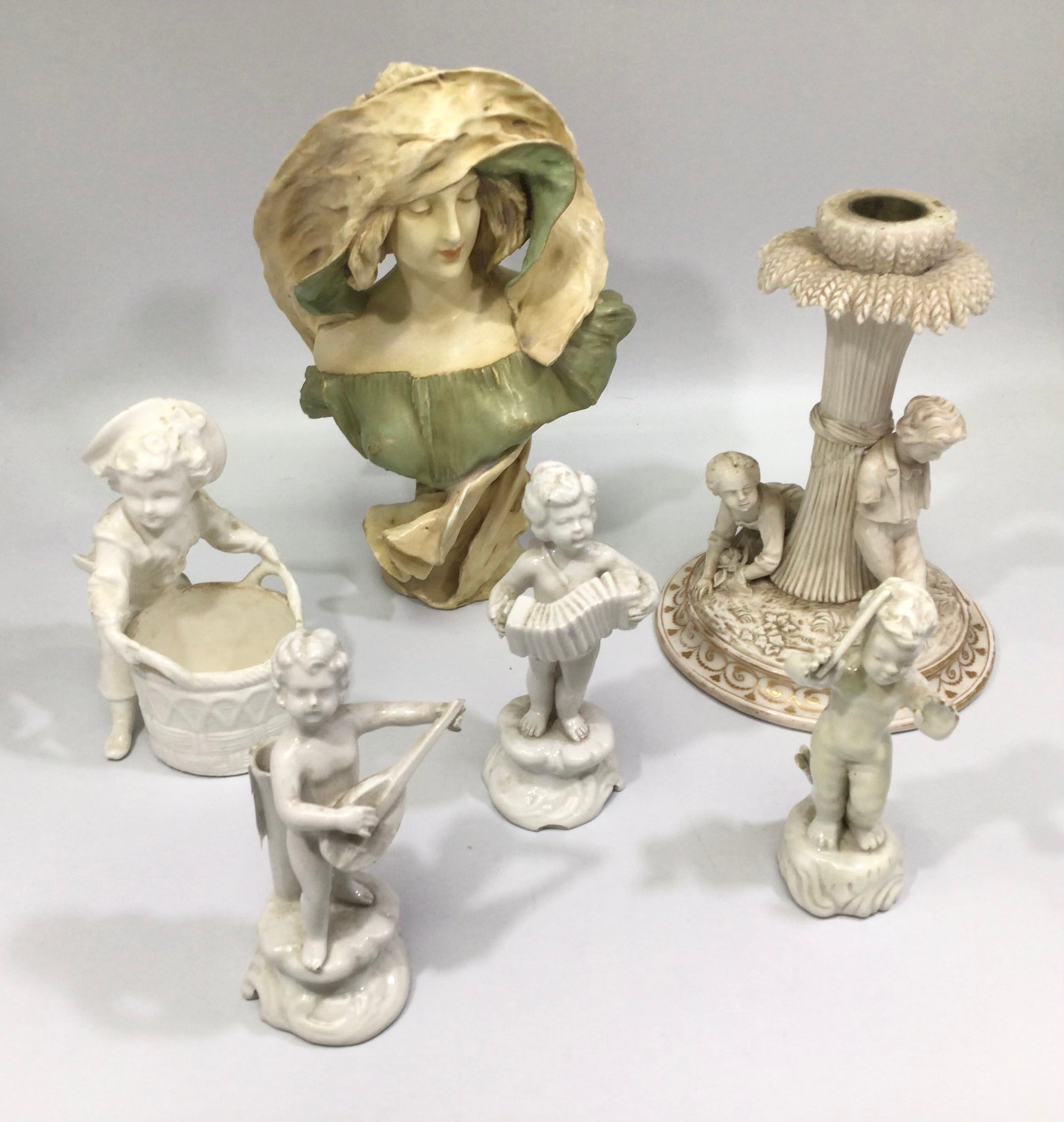 Three white German porcelain musical putti on scrolled bases, with an accordion, flute and mandolin,