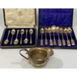 A George V silver cream jug together with a set of six fiddle pattern teaspoons with matching