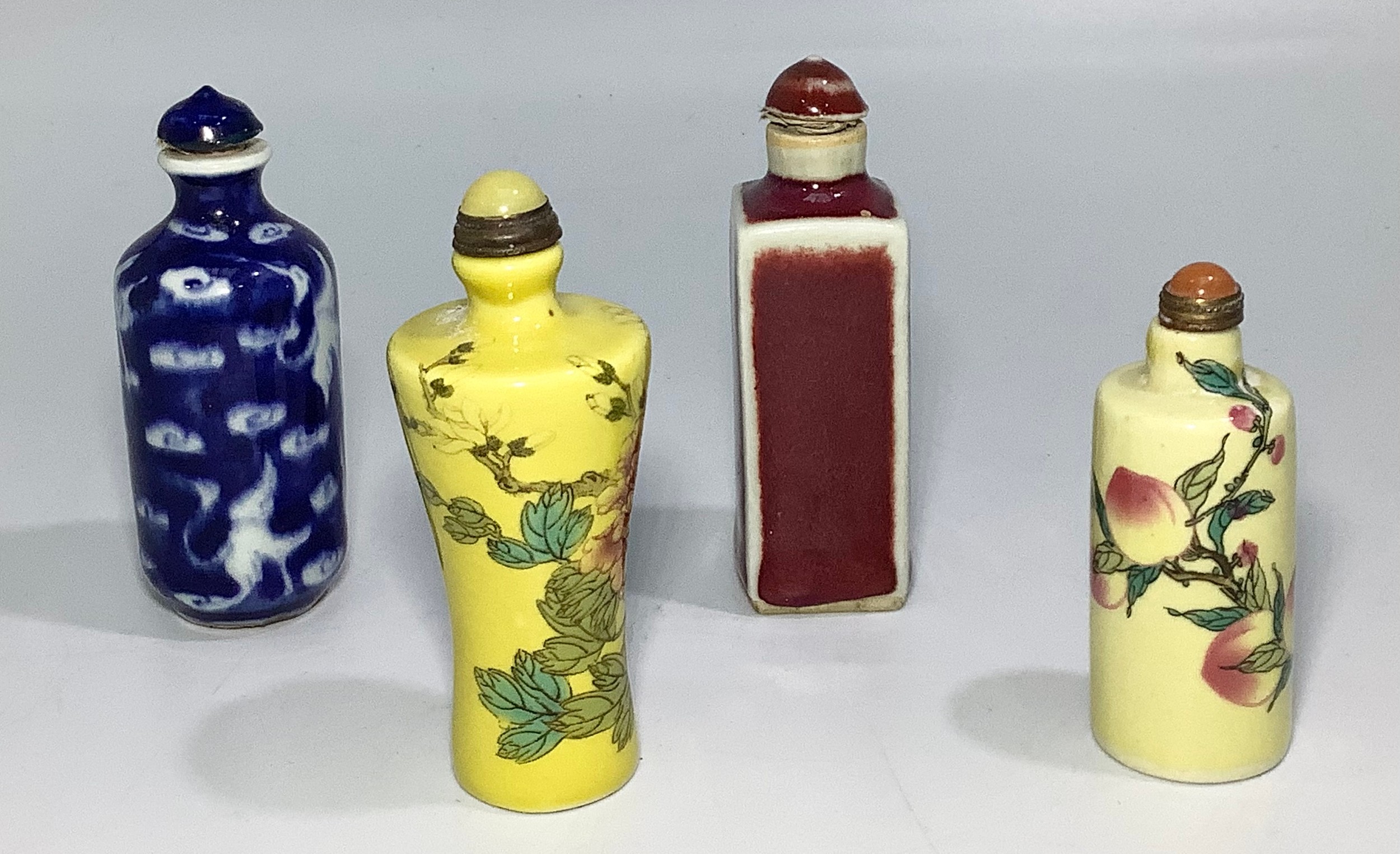 Four various Chinese snuff bottles including a yellow example with flowers, a blue and white example