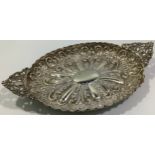 A late Victorian heavily embossed oval dish with floral and figural pierced pointed handles, London,