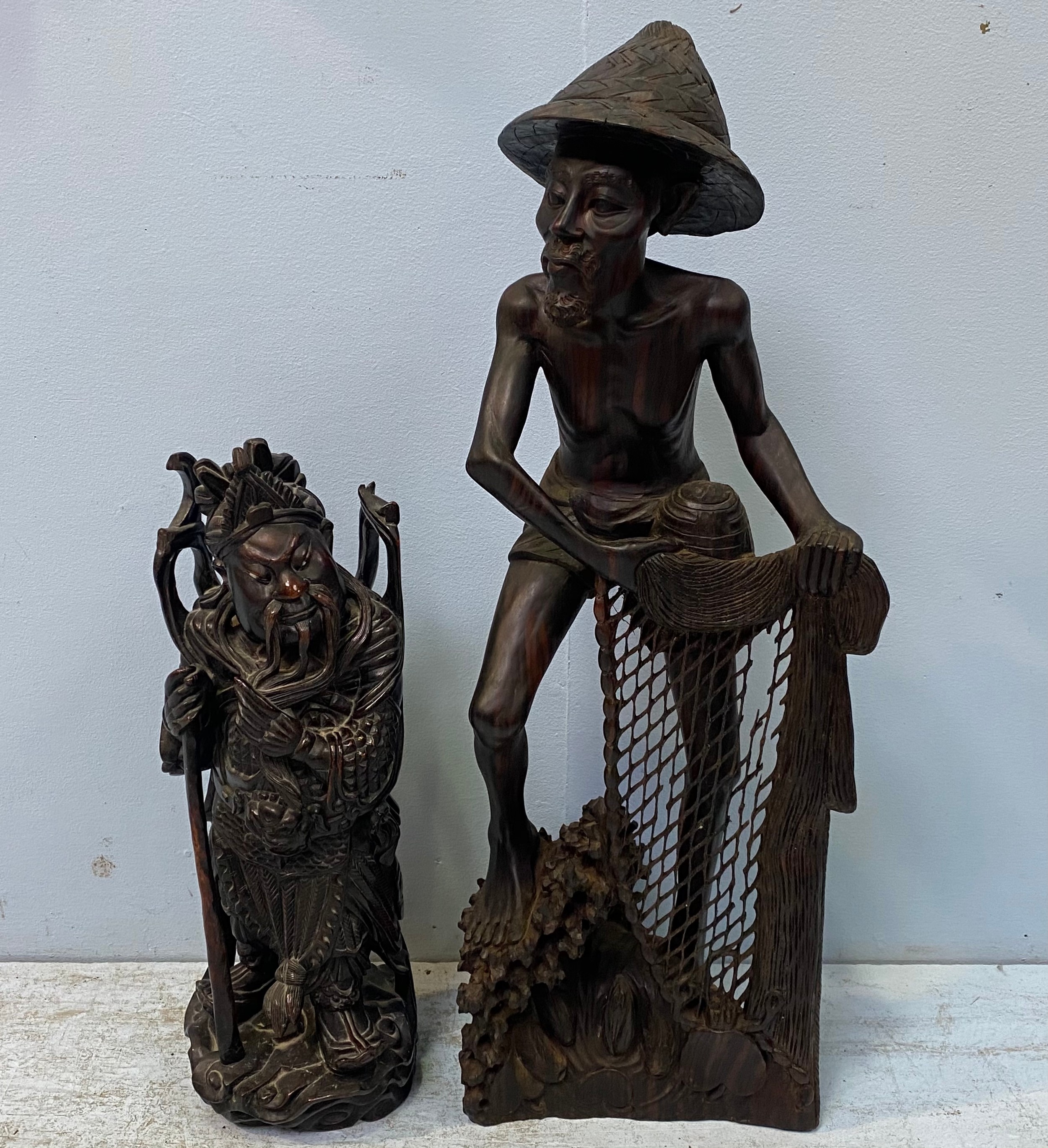 A South East Asian carved hardwood figure of a fisherman drawing his nets, 80cm high, and a