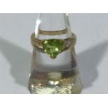 A 9ct gold Peridot and diamond ring, centrally three-claw-set with a trilliant cut peridot,
