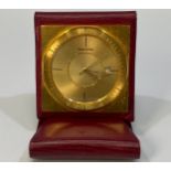 A Jaeger LeCoultre travel clock with gilt dial and square back plate, batons denoting the quarter