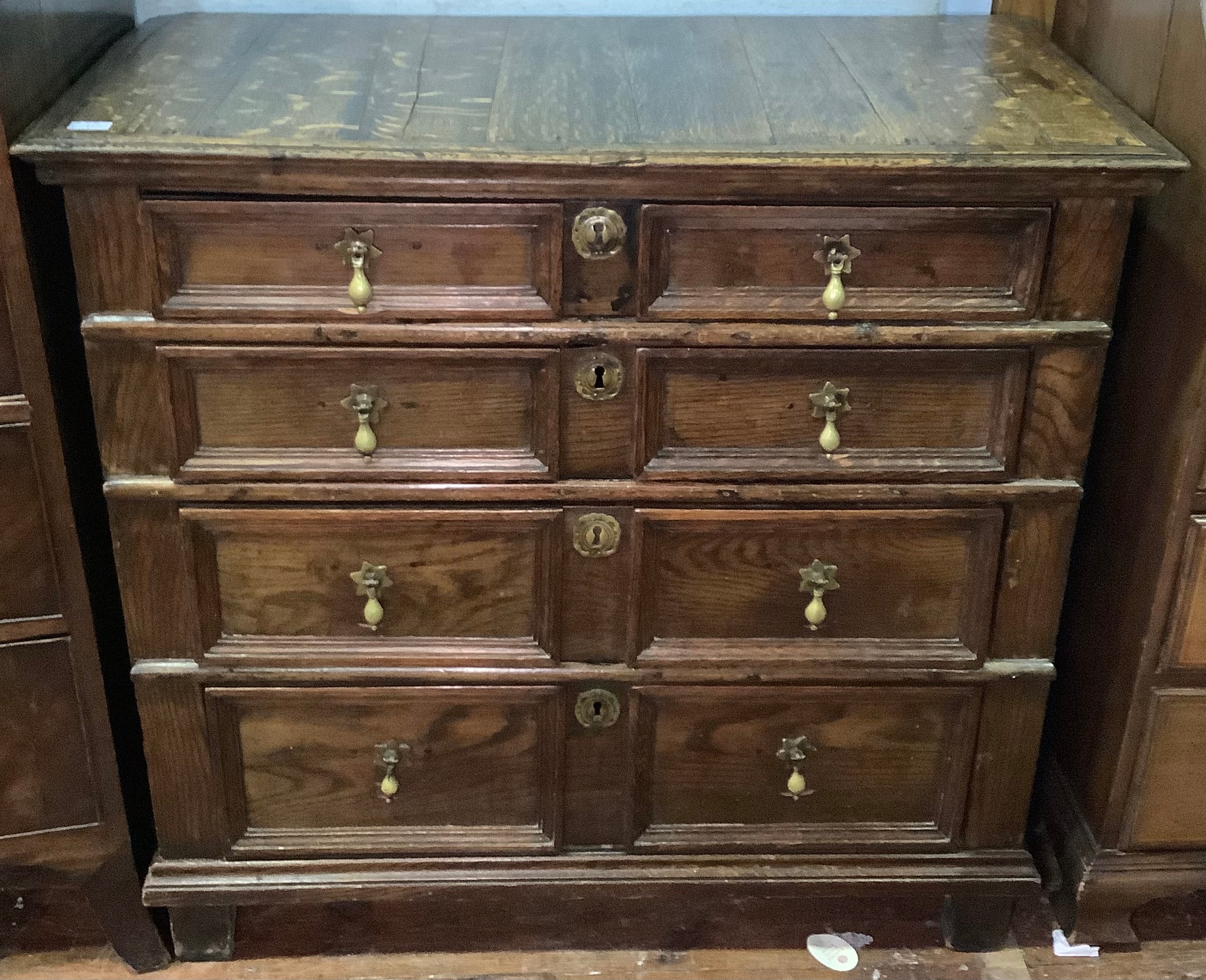 A 17th century oak chest of four long, graduated drawers with panelled fronts, brass drop pulls