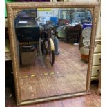 A large gilt-painted rectangular overmantel mirror with applied bows to corners, beaded top and