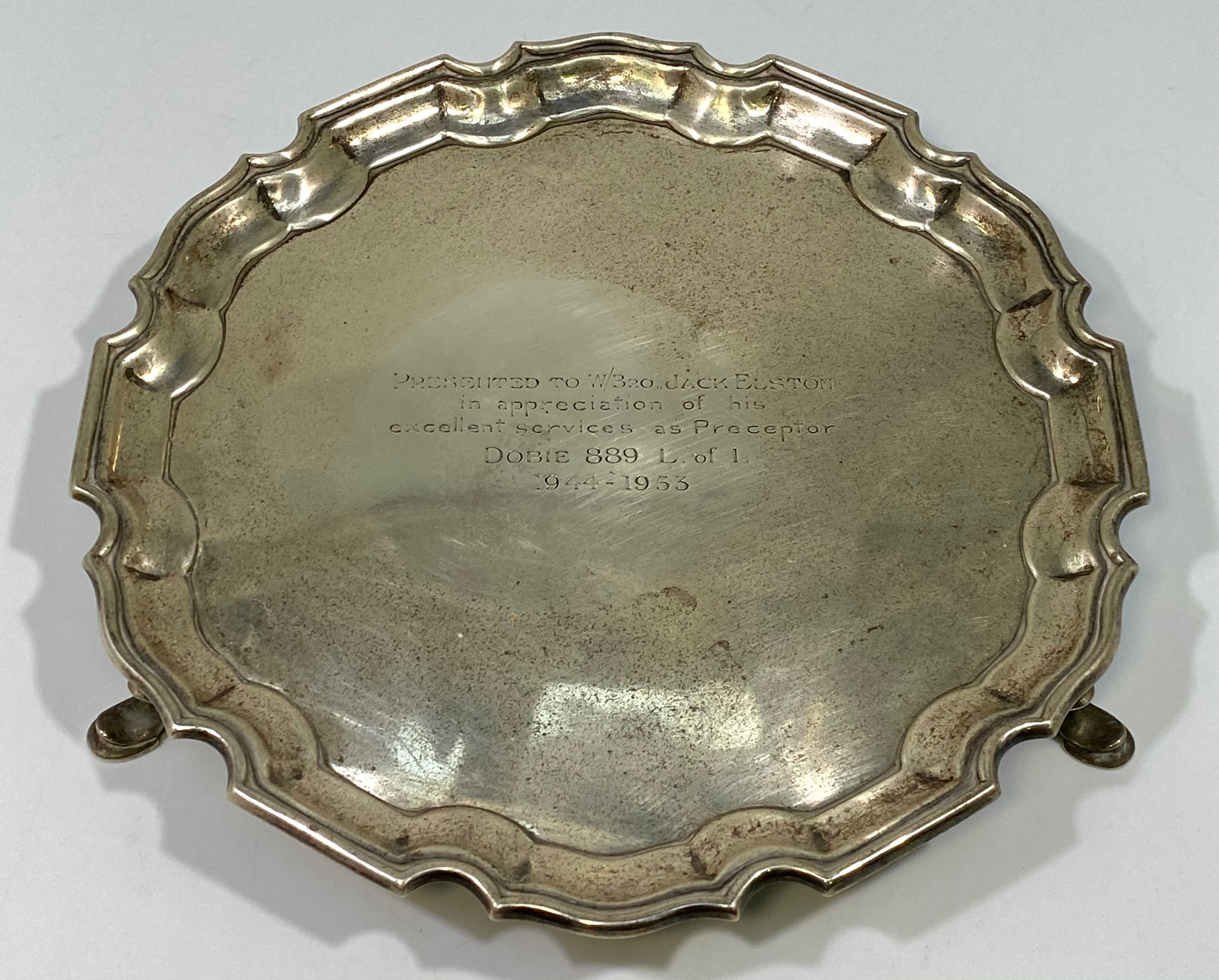 A silver salver with shaped rim, inscription to centre, raised on three pad feet, Sheffield, 1930,