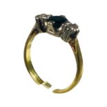 An 18ct yellow gold three stone ring, set with a round faceted dark blue sapphire to the centre, and