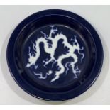 A Chinese porcelain 'scarificial blue' dragon dish, with white reserved dragon to richly applied